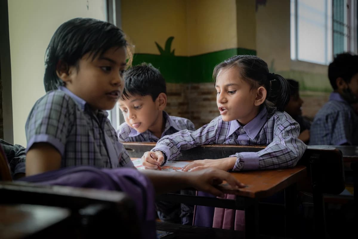 Three young students discussing their work at a shared desk