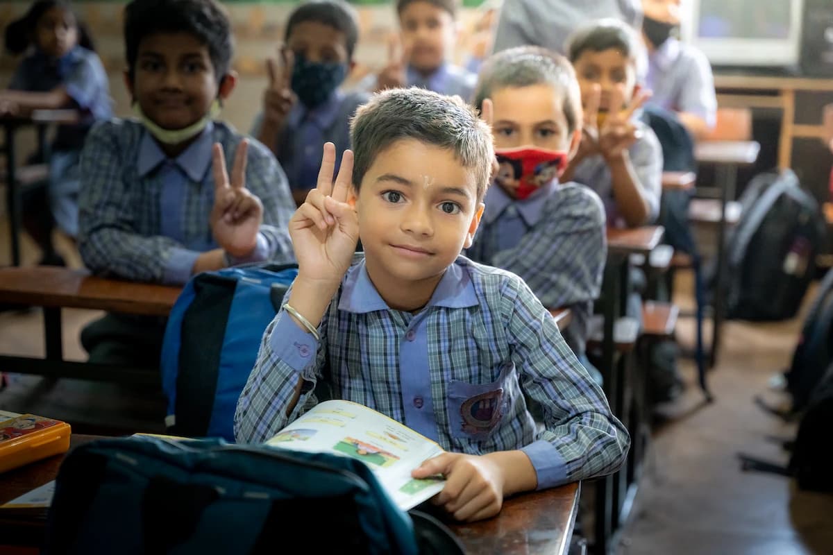 Young student flashing a peace sign at his desk