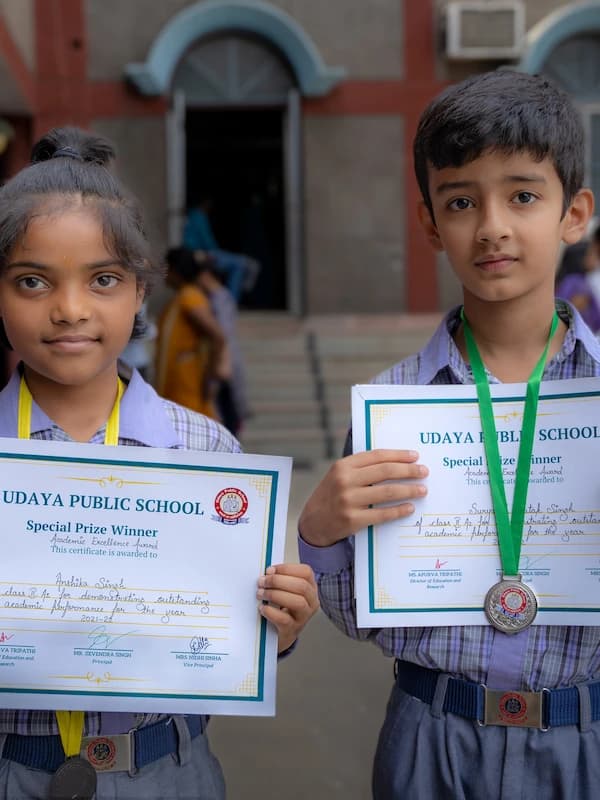 Two young prize winners holding up their award certificates