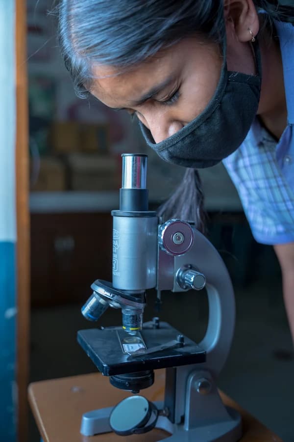 Student examining a slide through a microscope in the science lab