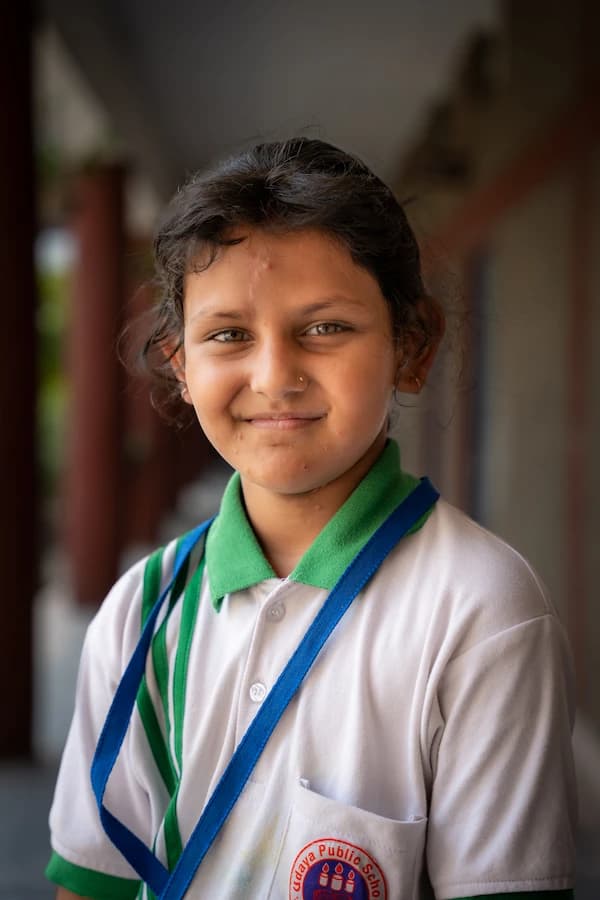 A smiling student in braids wearing the school uniform