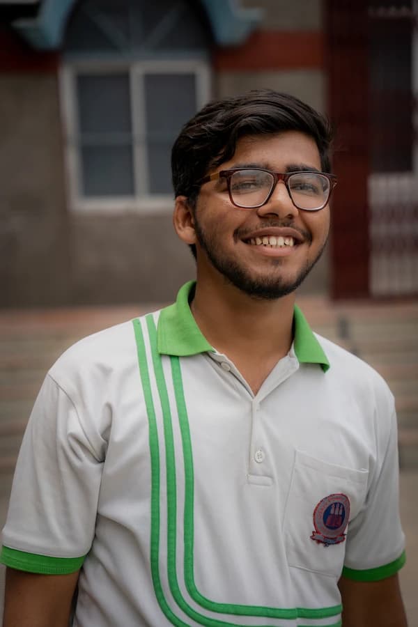A young student smiling with his house sash on