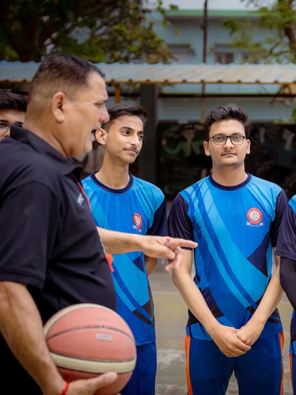 A coach instructing two players during basketball practice