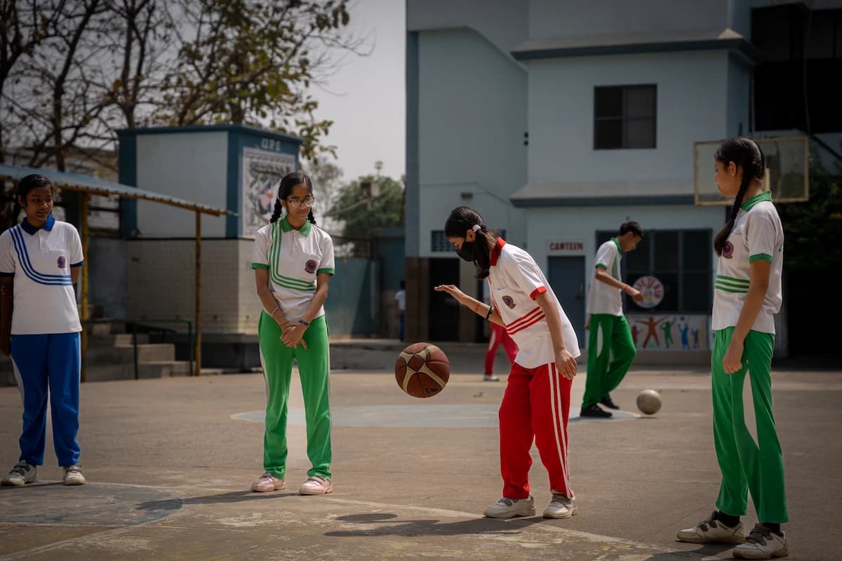 Students in house colors playing basketball on the school court