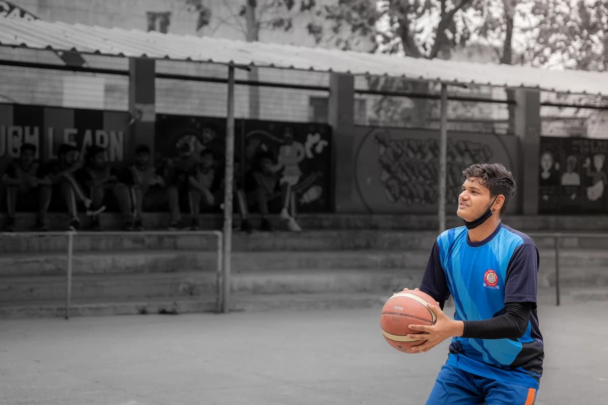 A player in school jersey dribbling a basketball on the court