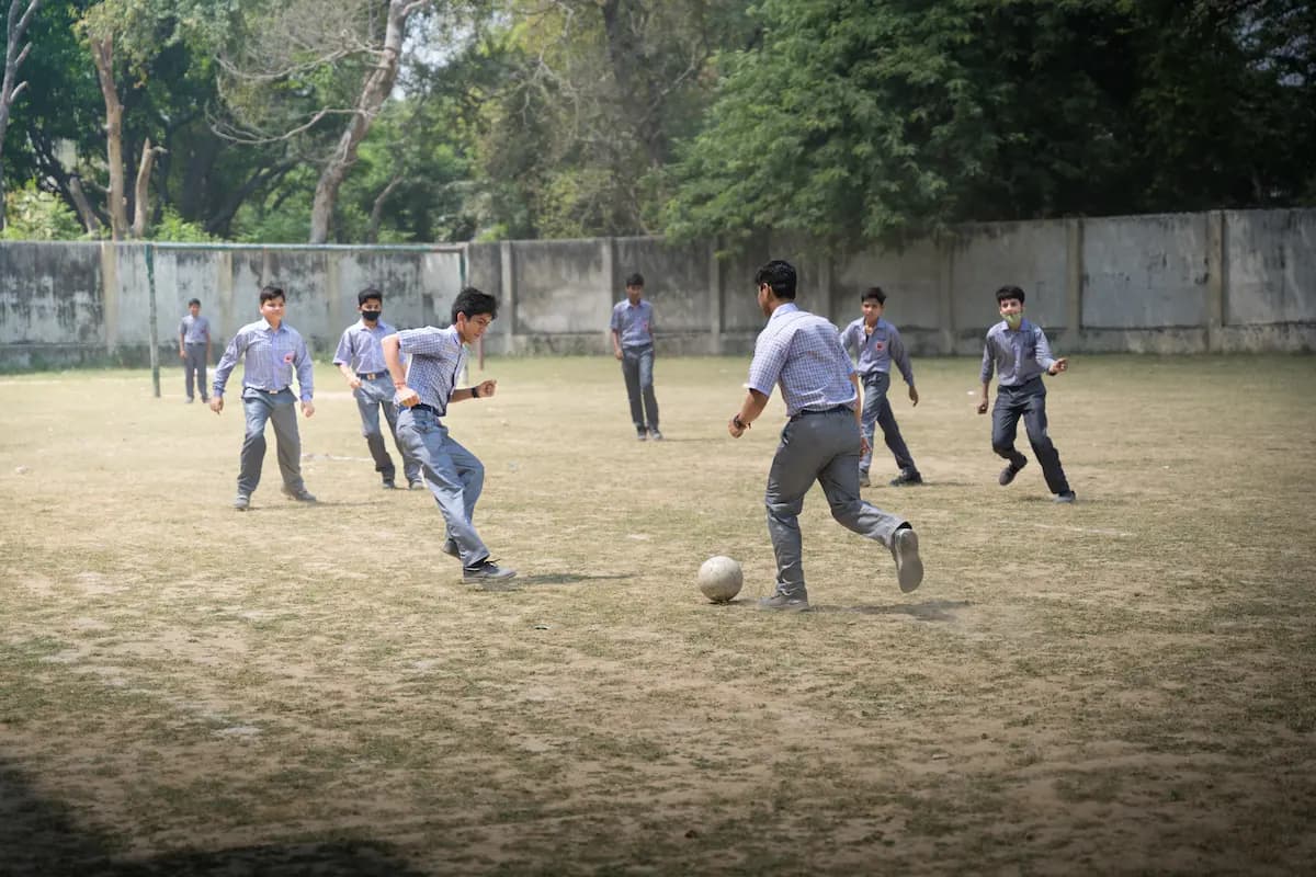 Students chasing the ball during football practice on the field