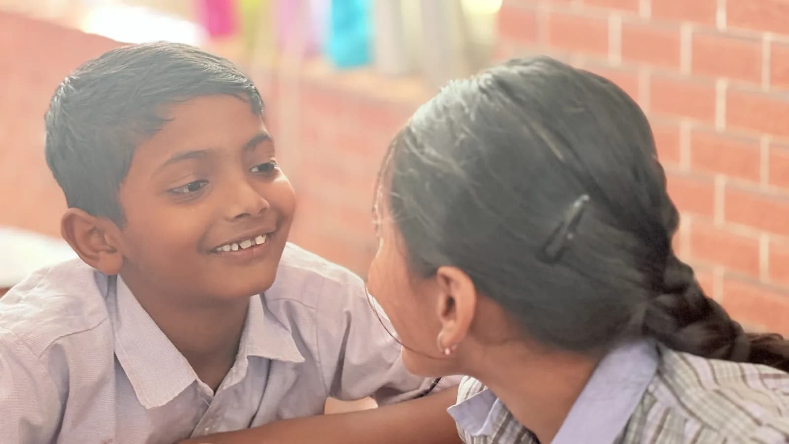 An older student listening to a younger child at Udaya Public School, Ayodhya